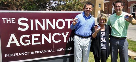 Kyle, Dustin, and Pam posing in front of The Sinnott Agency sign.